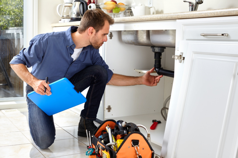 plumber inspecting pipes kitchen
